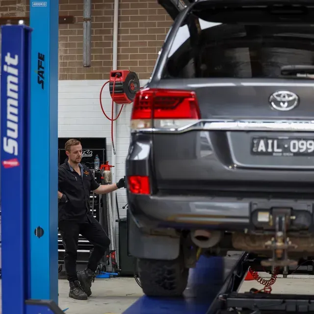 Mechanic Working on a Grey Suv Raised — COOTA Automotive Services in Ballarat East, VIC