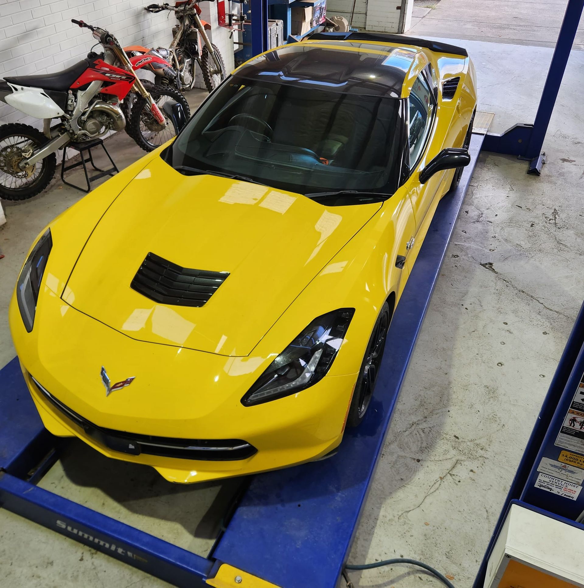Yellow sports car on a lift in a garage. — COOTA Automotive Services in Ballarat East, VIC