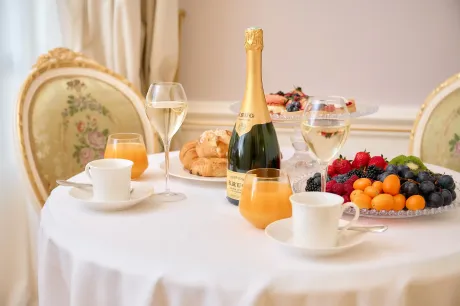A table with a bottle of champagne , juice , fruit , and coffee.
