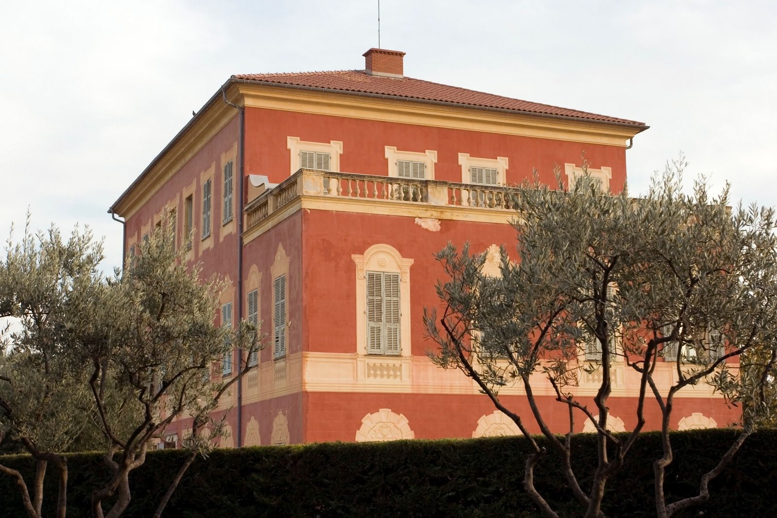 A large red building with a balcony and trees in front of it