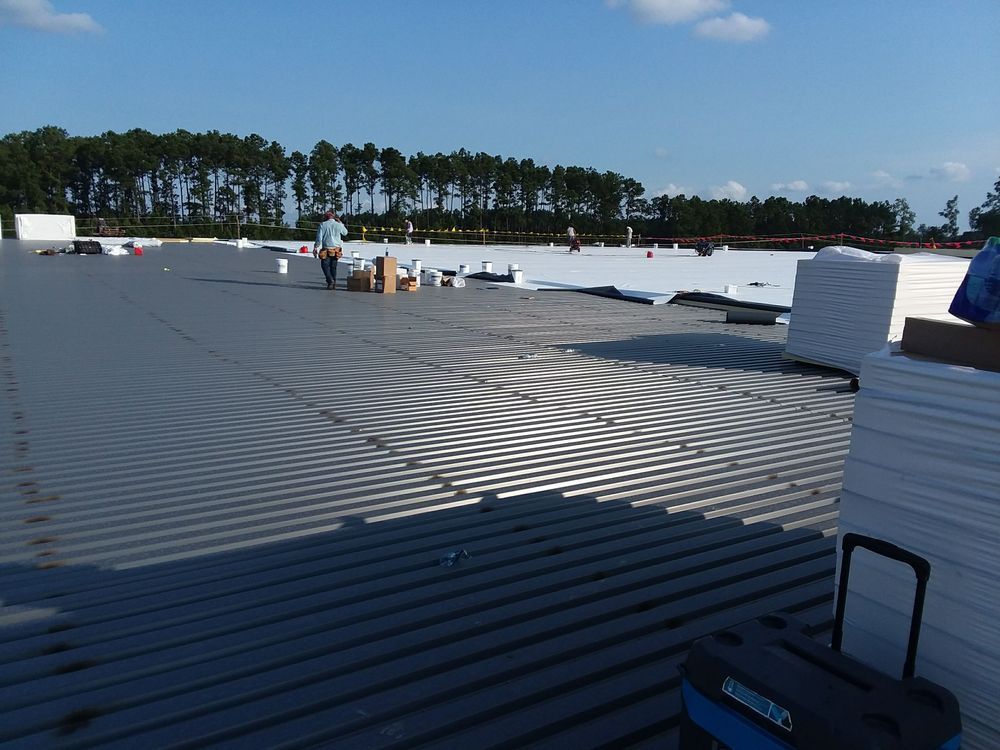 Construction site: Workers on a large, corrugated metal roof.