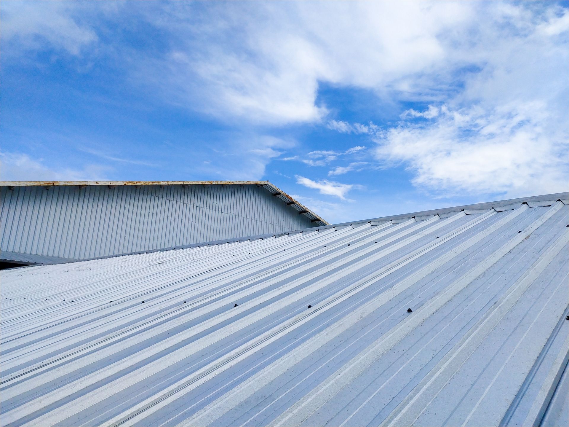 Metal corrugated roof against a blue sky with clouds.