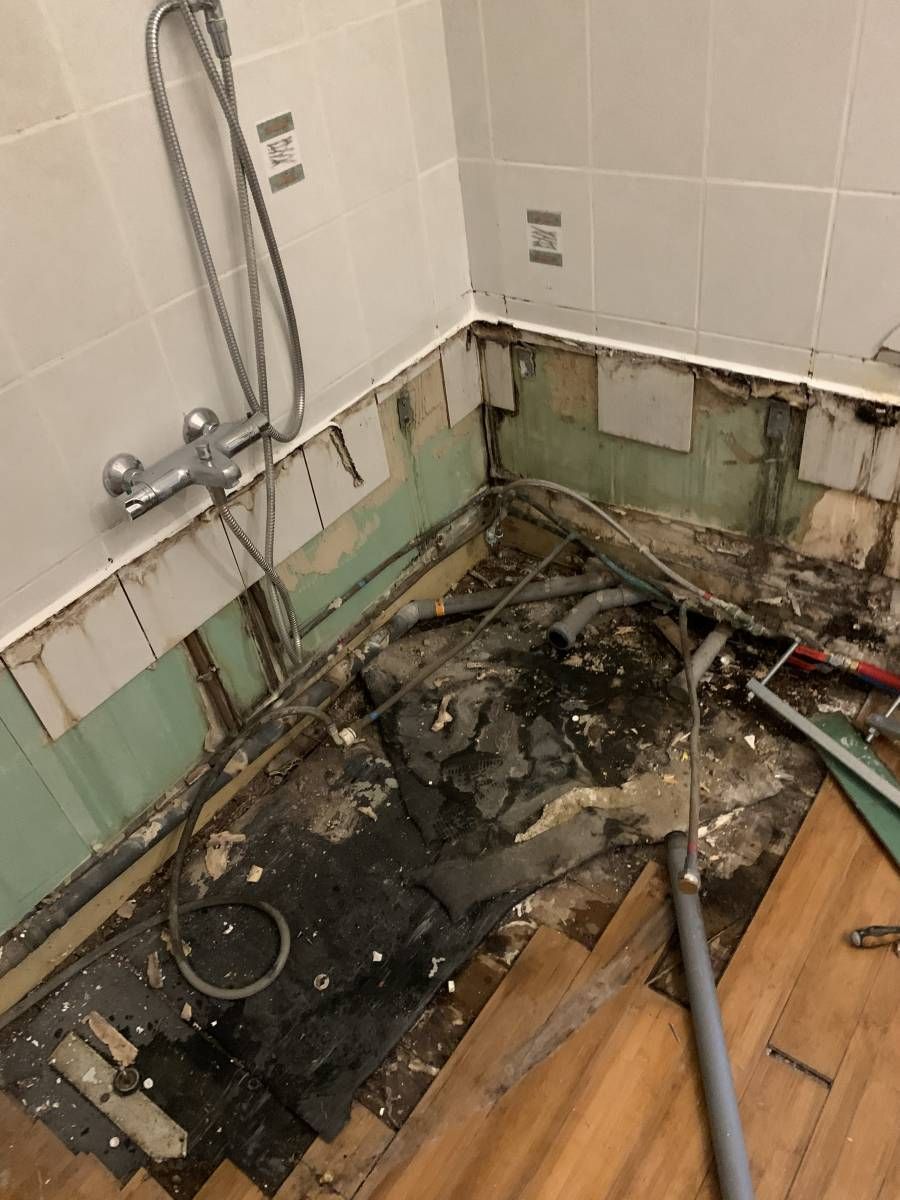 Une salle de bain avec une douche et un trou dans le sol.