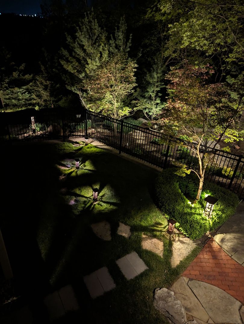 Premium outdoor lighting fixture casting warm amber light across stone architectural feature at night