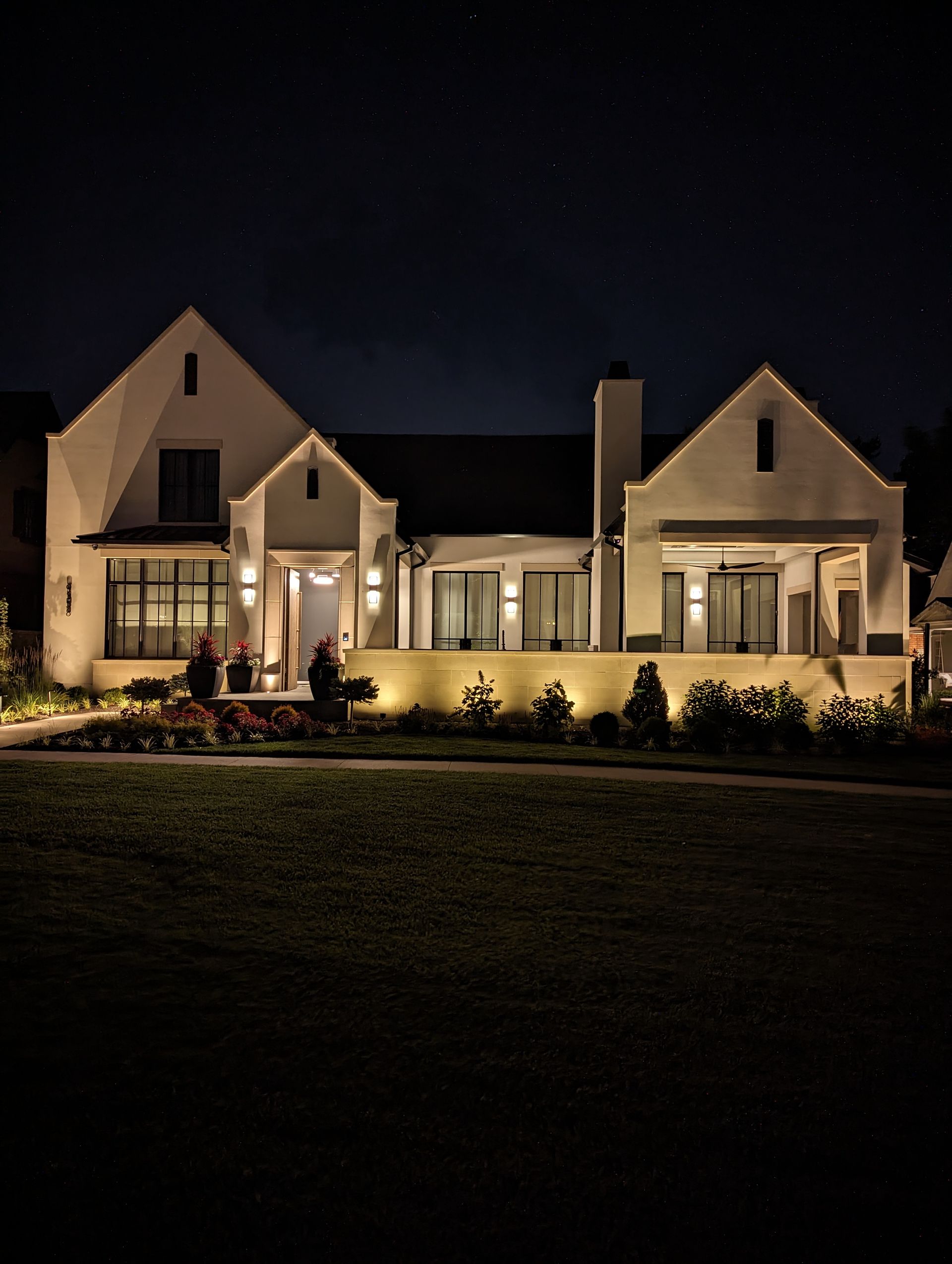 Technician inspecting landscape lighting fixture at dusk