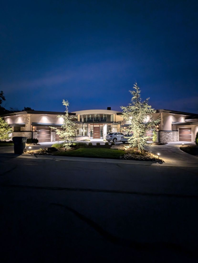 Technician inspecting landscape lighting fixture at dusk