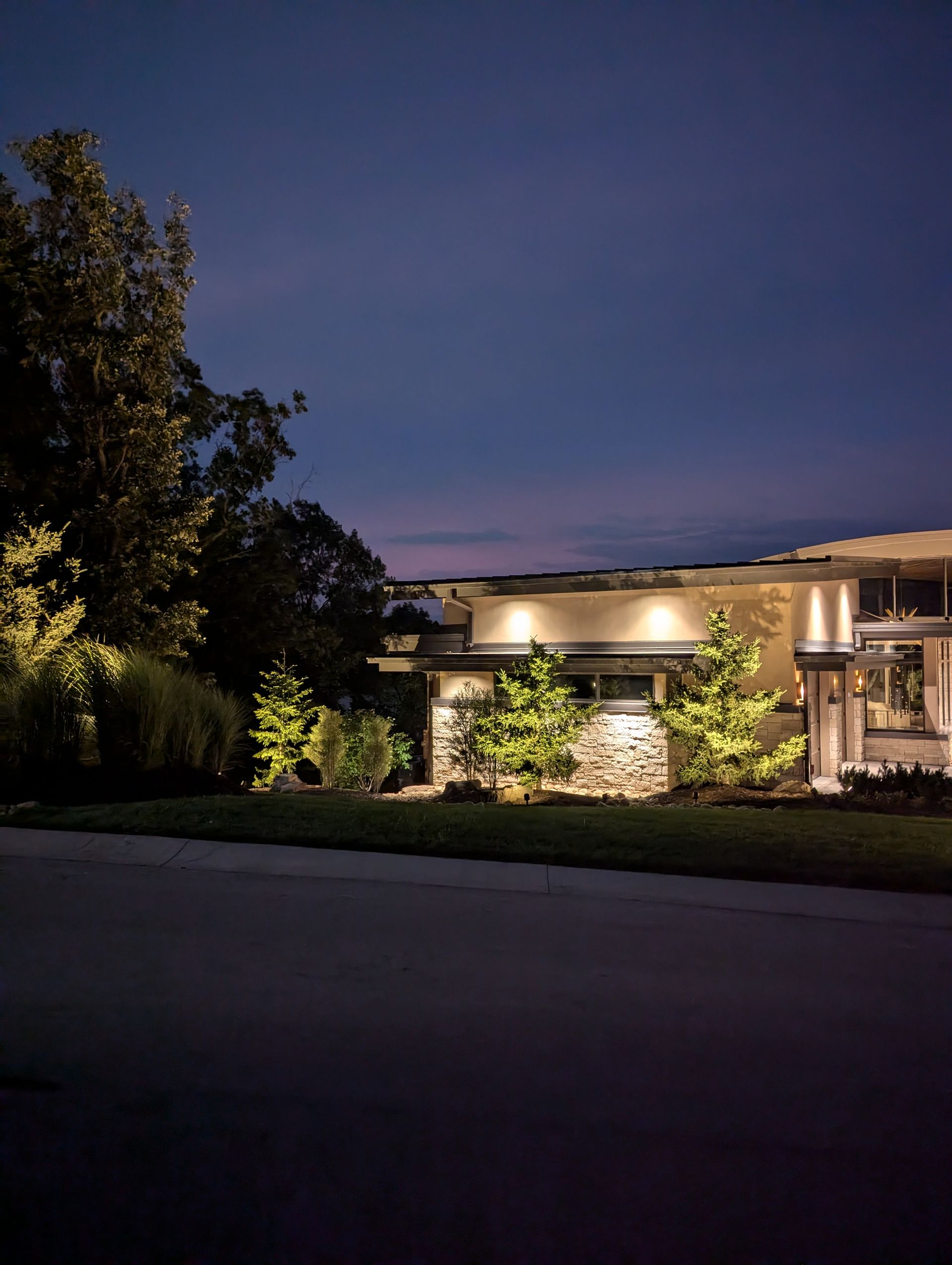 Luxury residential property with warm amber landscape uplighting at night