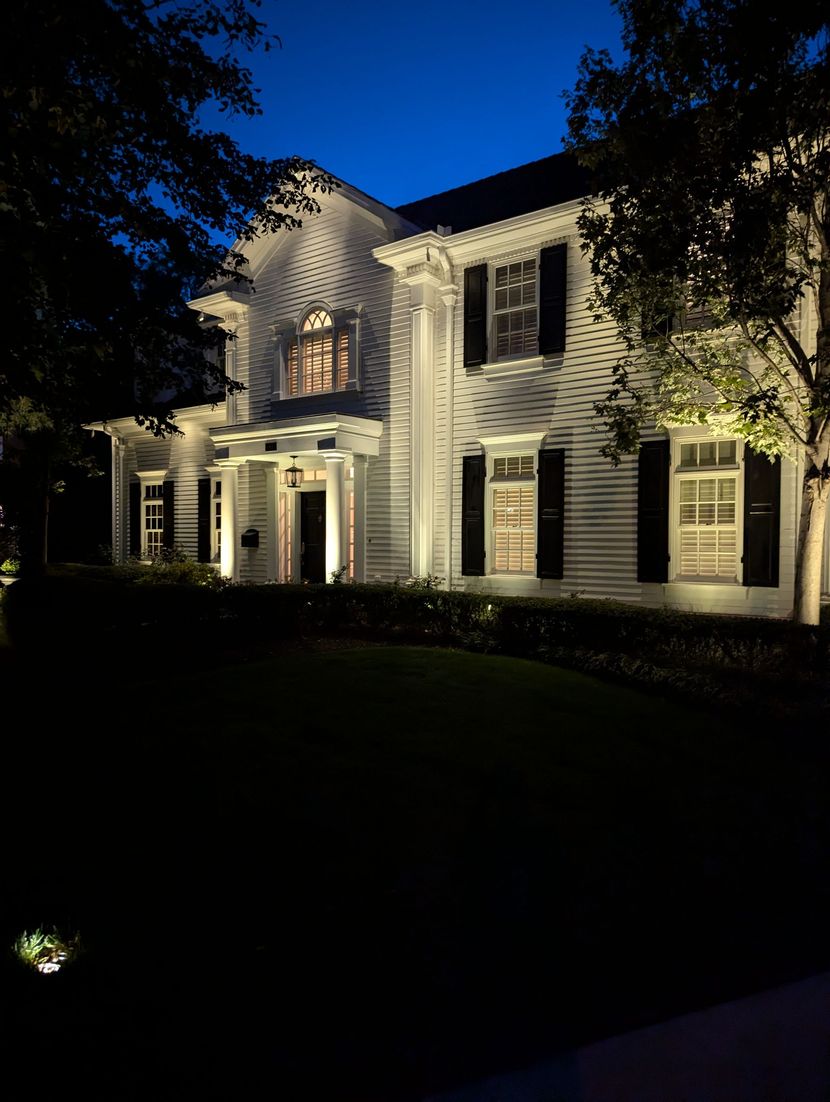 Luxury residential property with warm amber landscape uplighting at night