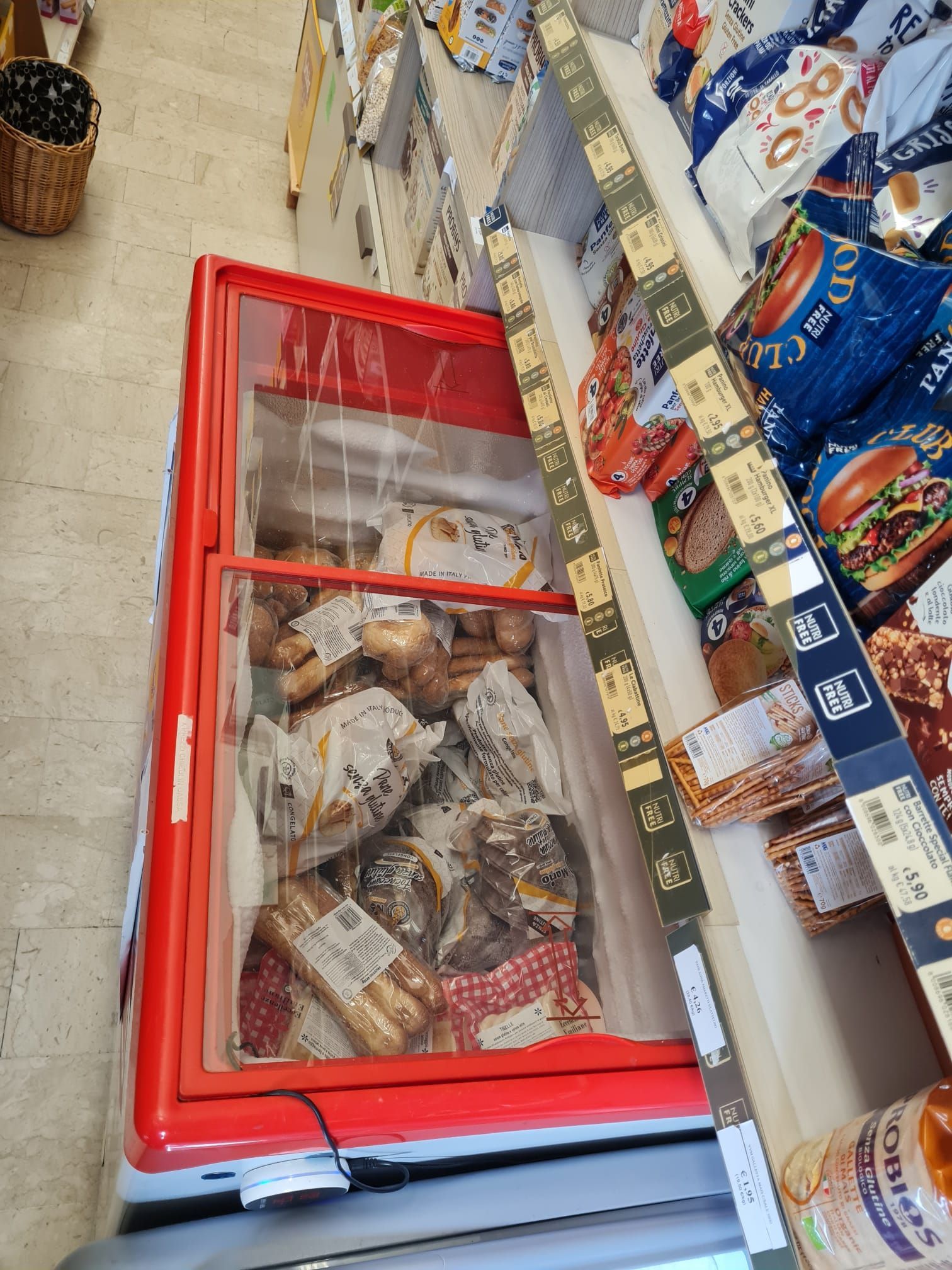 Vista dall'alto di un congelatore rosso pieno di alimenti surgelati confezionati in una corsia di un supermercato.