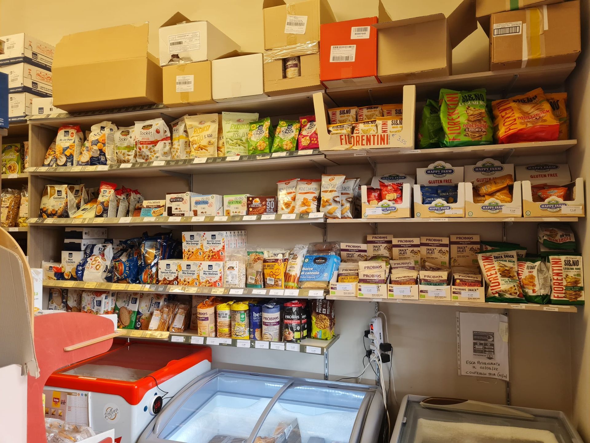 Un piccolo ripiano dispensa, sopra un congelatore a pozzetto, è rifornito di snack assortiti e prodotti confezionati.