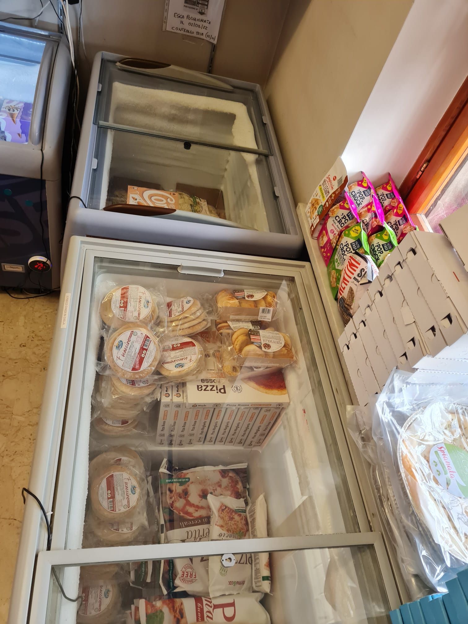 Congelatori a pozzetto aperti, pieni di alimenti surgelati, in una corsia di un supermercato.