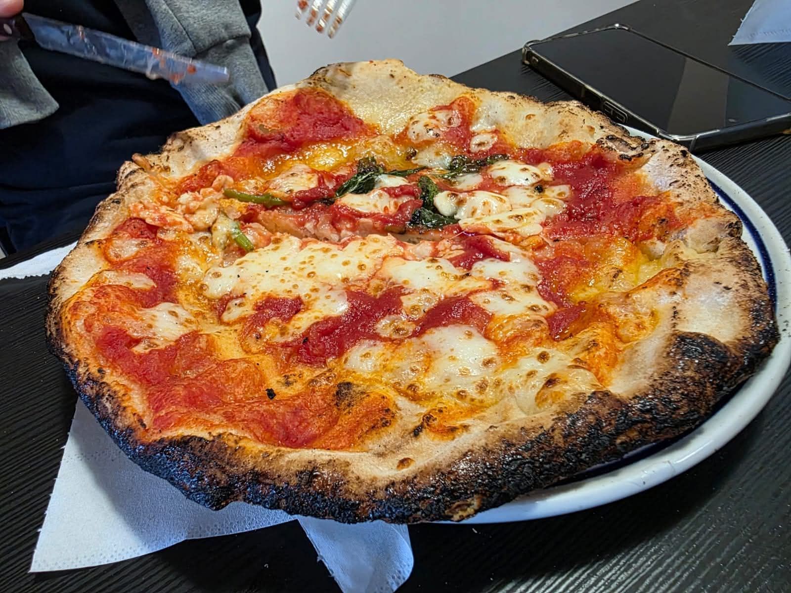 Una pizza appena sfornata con salsa di pomodoro e formaggio fuso su un piatto, servita a tavola.