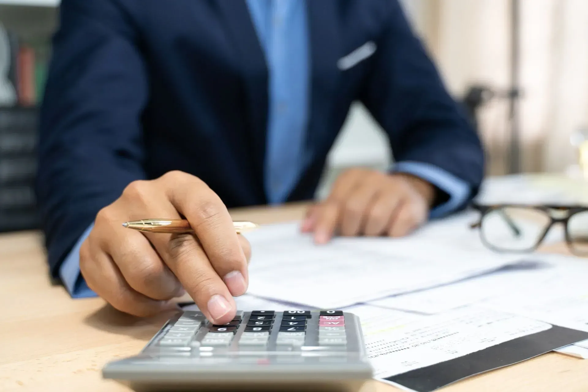 a man is using a calculator while holding a pen