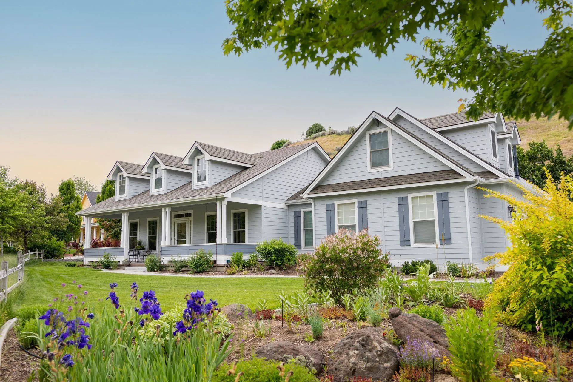 a large white house with a large porch and flowers in front of it