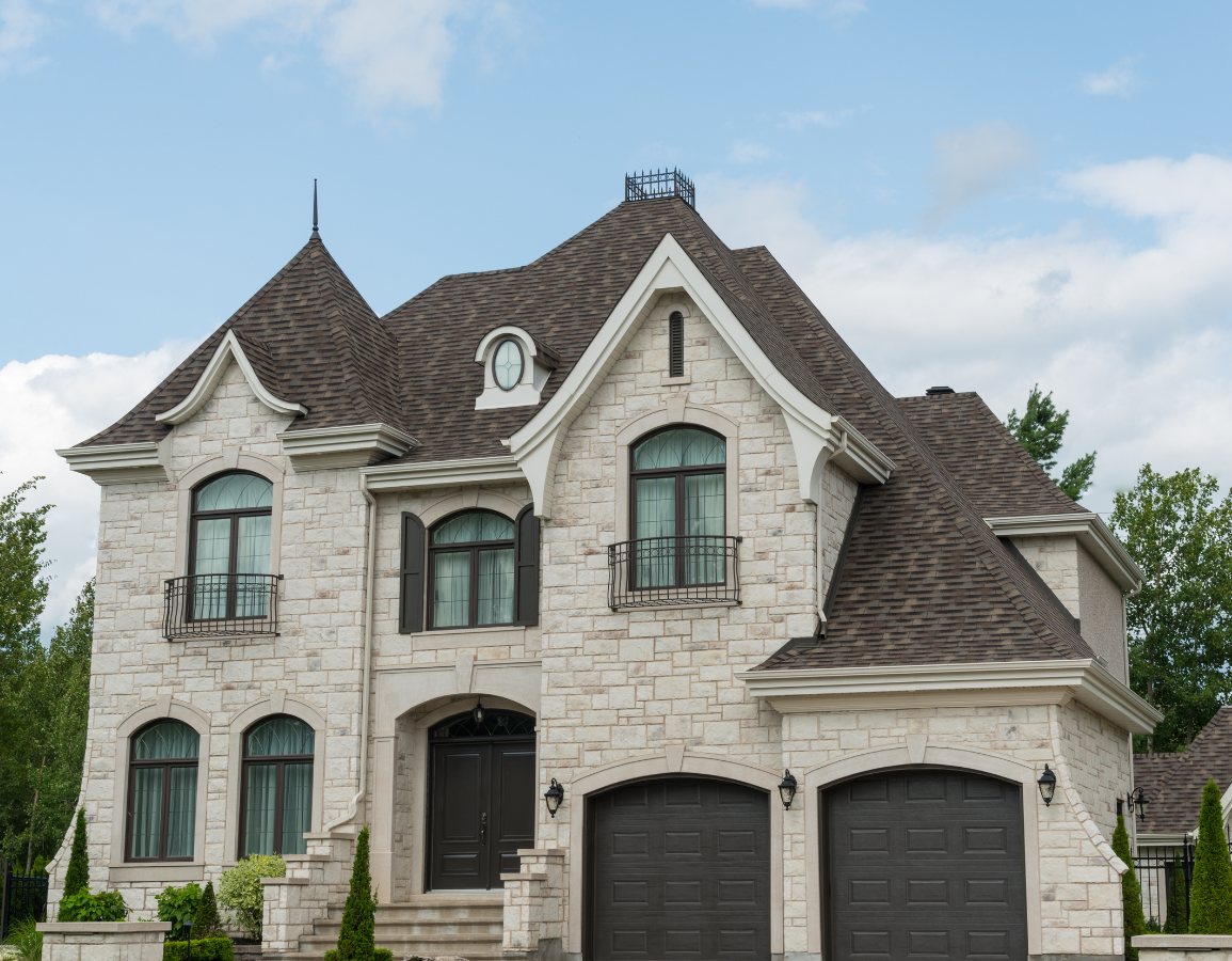 a large white brick house with two garages and a gray roof