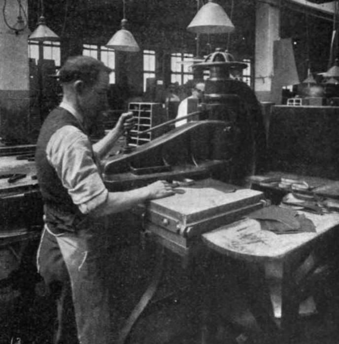 Man working at a machine cutting leather, industrial setting.