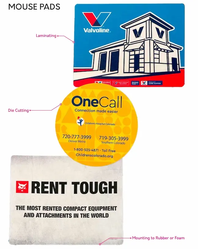 Three distinct mouse pads: a rectangular Valvoline pad, a circular yellow OneCall pad, and a square Bobcat