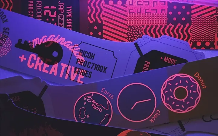 UV light illuminates paper with various designs and text, including the words