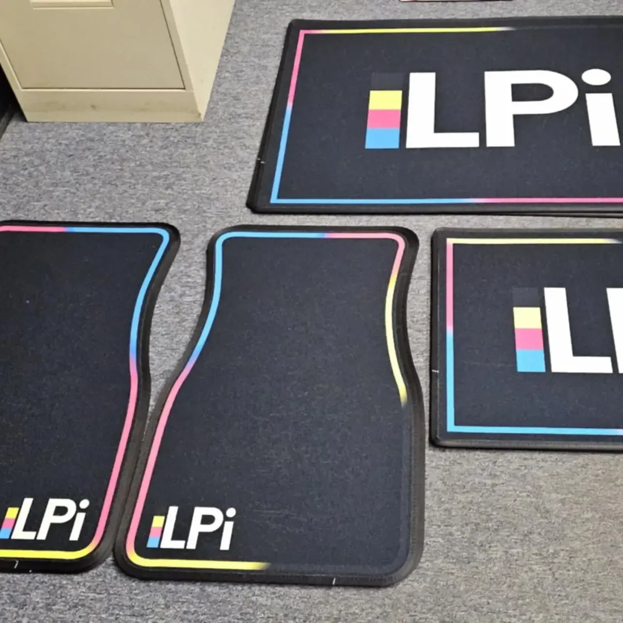 Four black floor mats with the logo