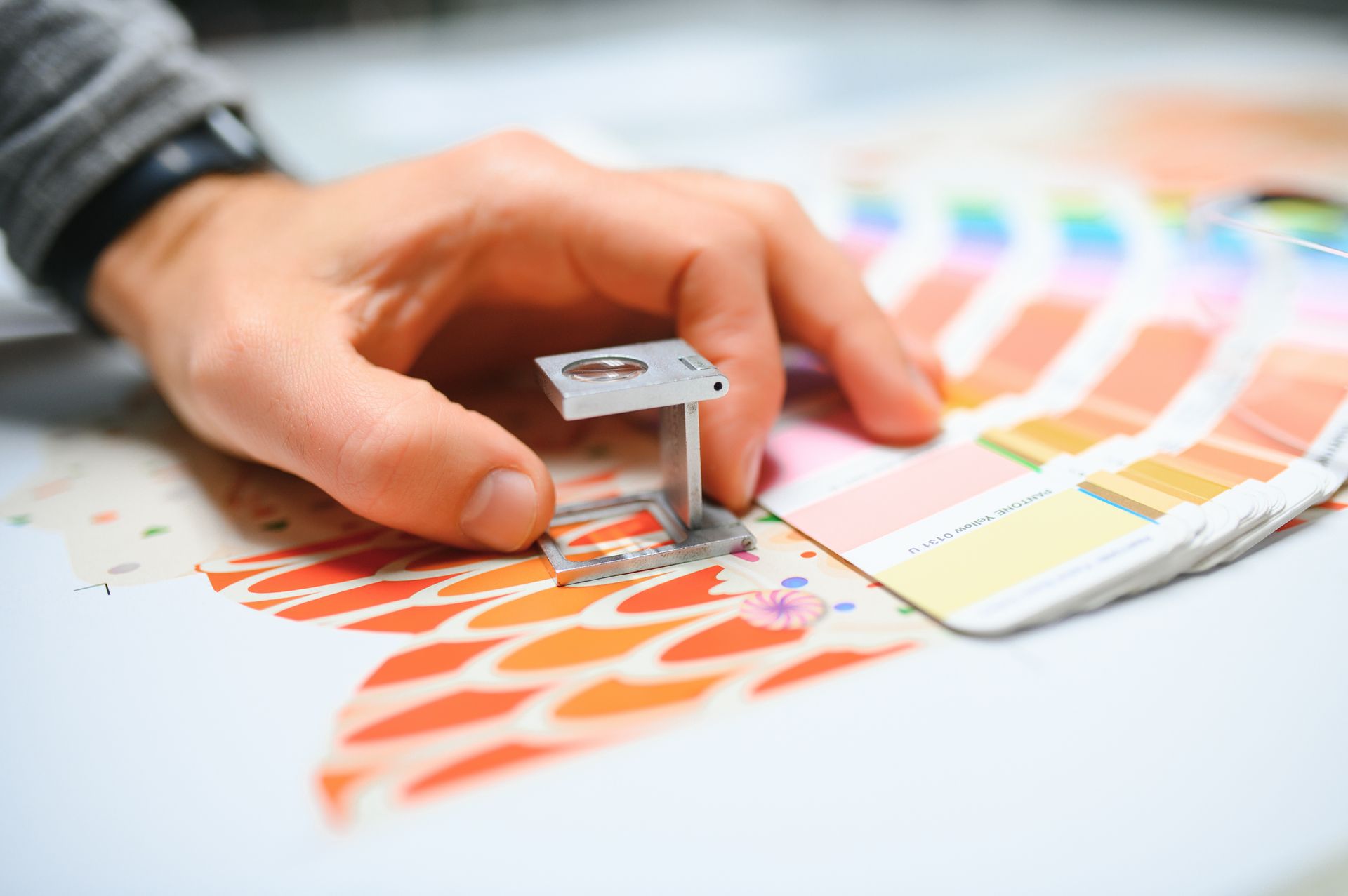 Hand holding a small, metallic table model with colorful swatch cards, and patterned paper.