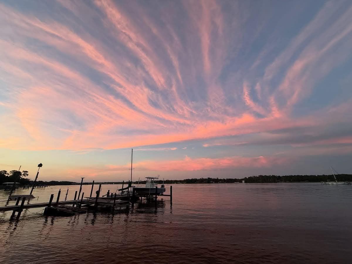 Pink and blue sunset over a calm river, boat docked at a pier.