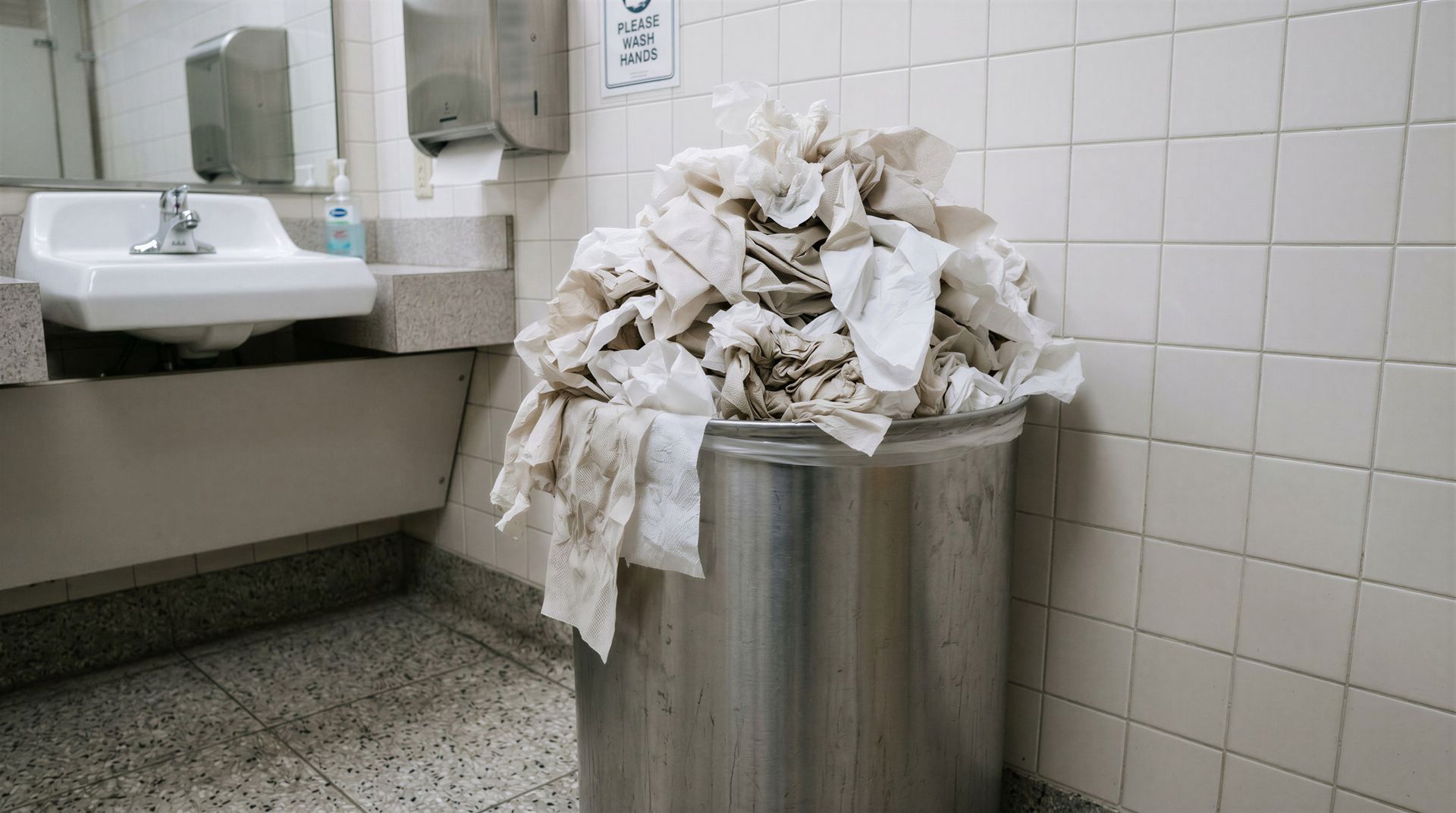 full trash can in dirty bathroom