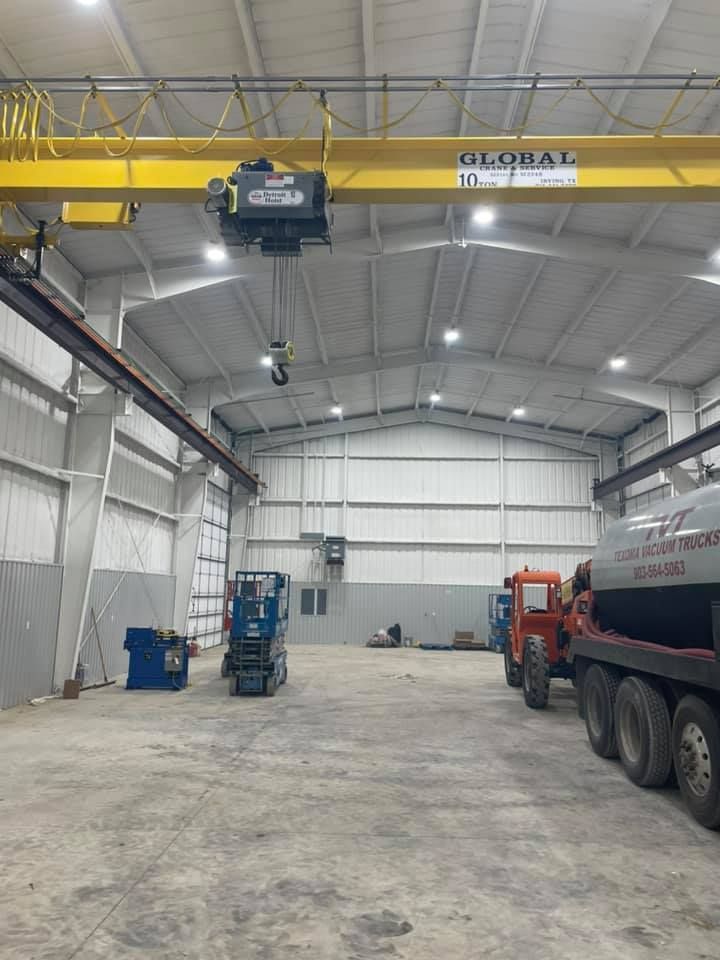A large warehouse with a crane and trucks in it.