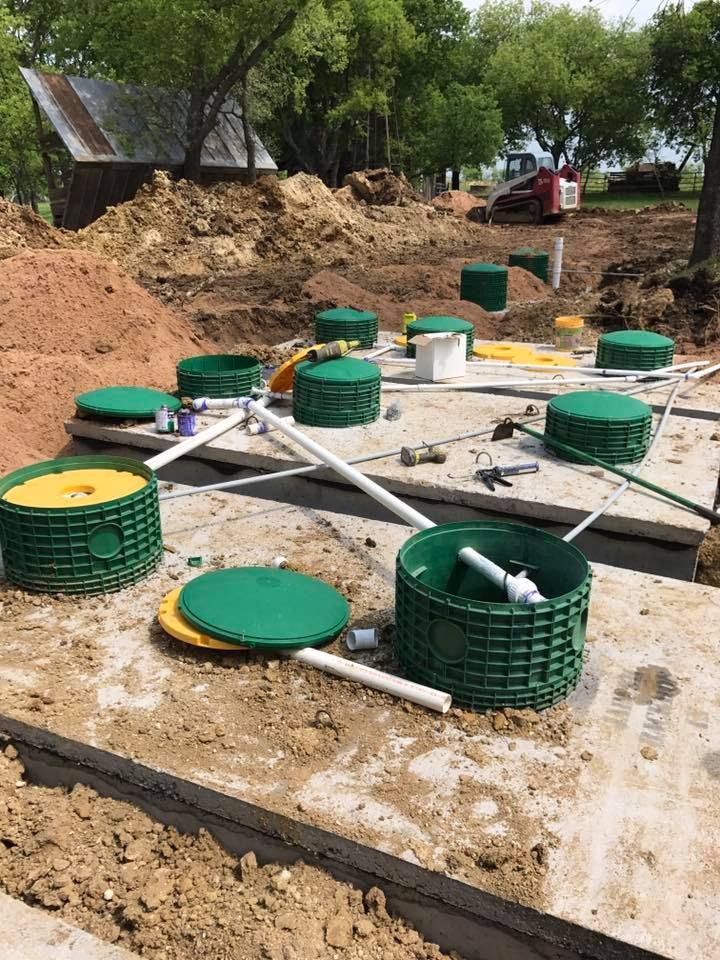 A septic system is being built in a dirt field.