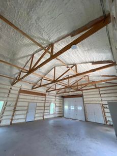 Interior view of a building's ceiling and roof structure with red framing and overhead lighting.