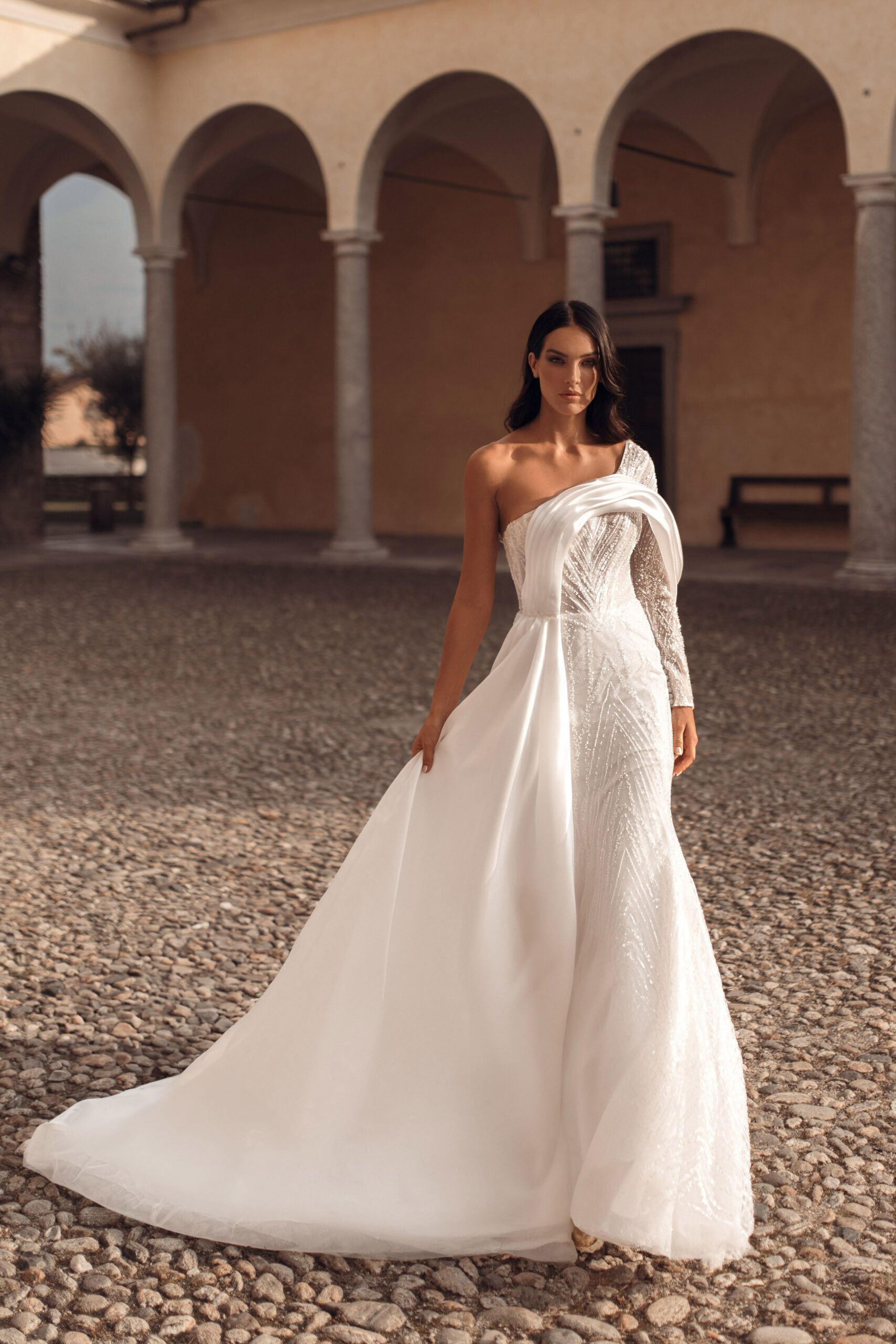 Donna in un abito da sposa scintillante con maniche e strascico fluenti