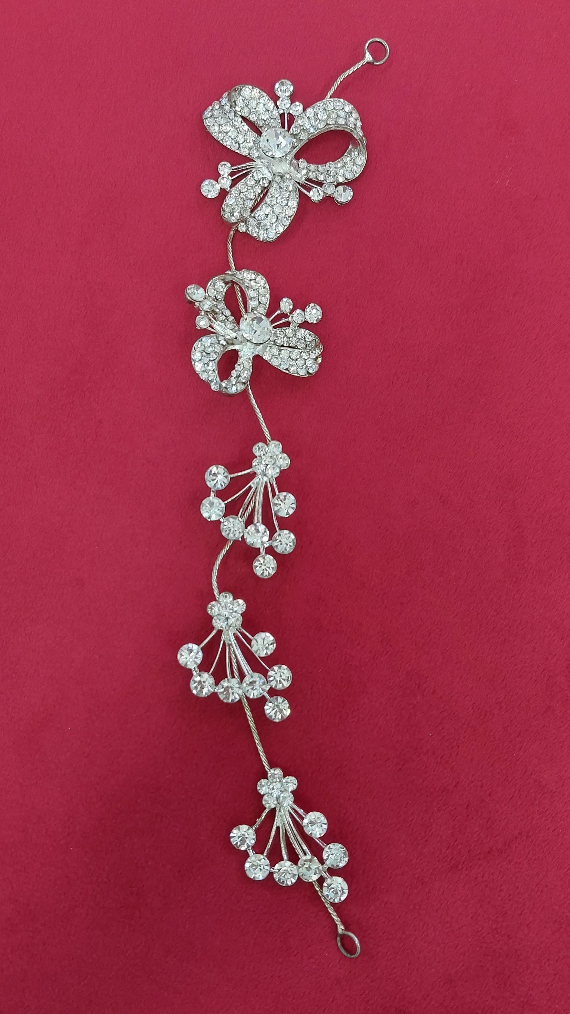 Fermaglio per capelli da sposa in argento con strass trasparenti, su sfondo rosso.