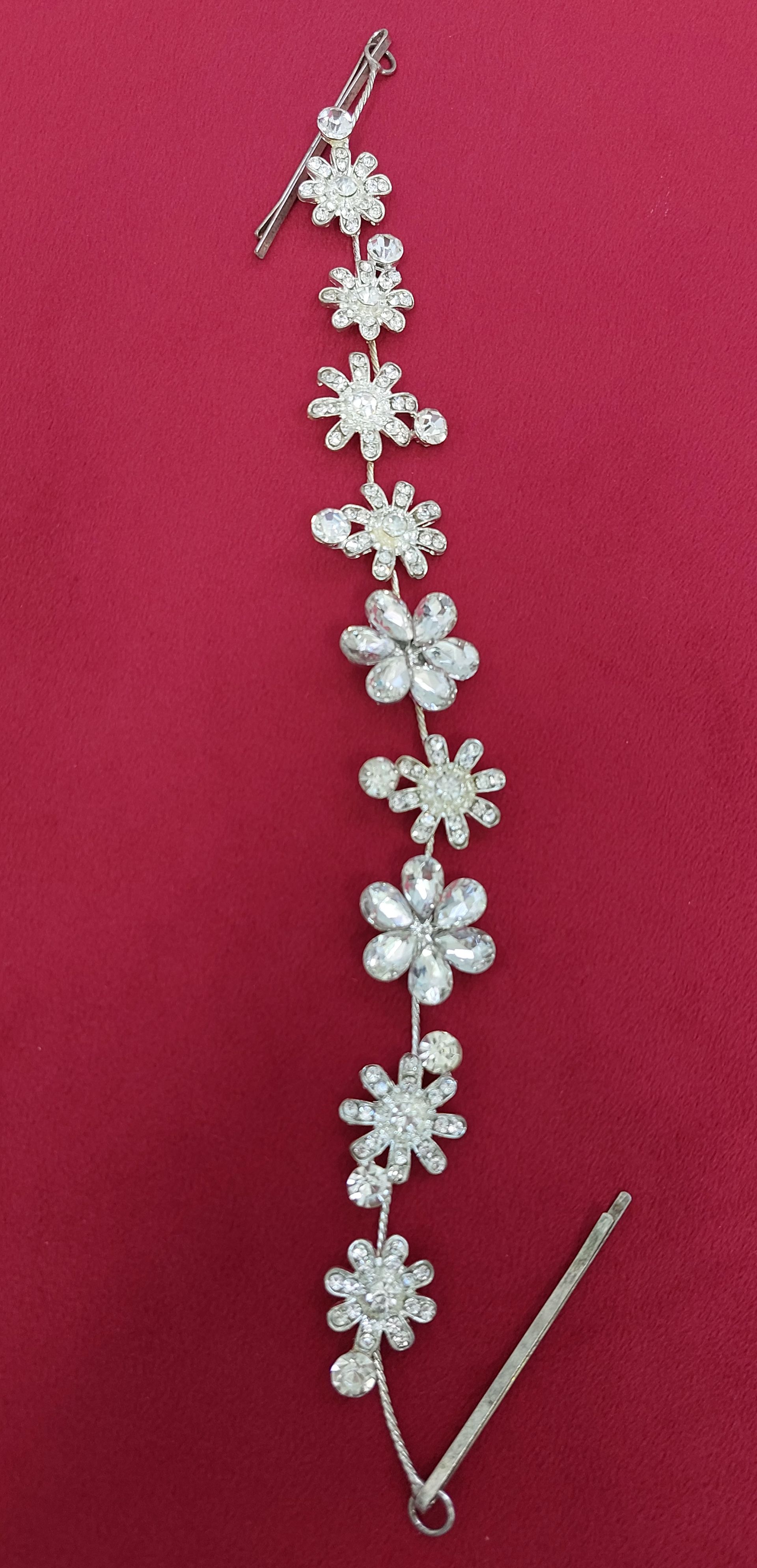 Accessorio per capelli floreale argentato su sfondo rosso.