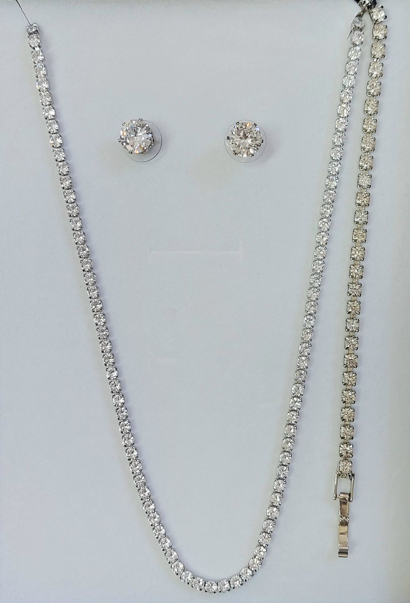 Collana, orecchini e bracciale di diamanti incastonati su sfondo bianco.