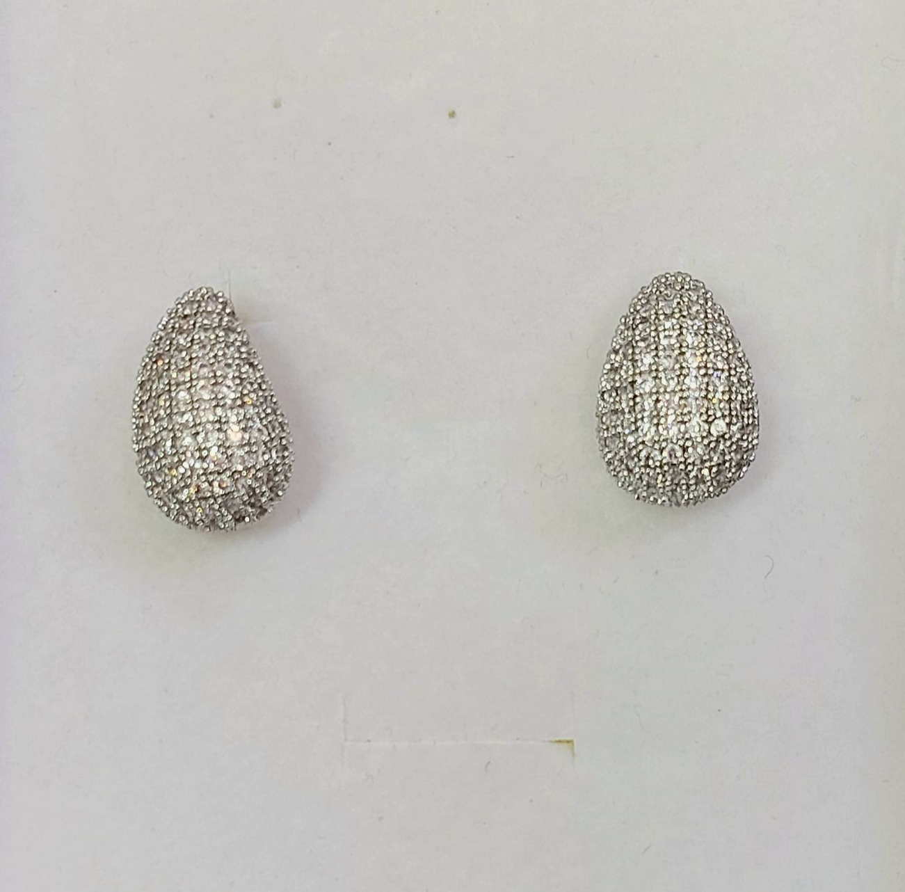 Orecchini in argento a forma di lacrima, tempestati di piccoli diamanti, incastonati su uno sfondo chiaro.