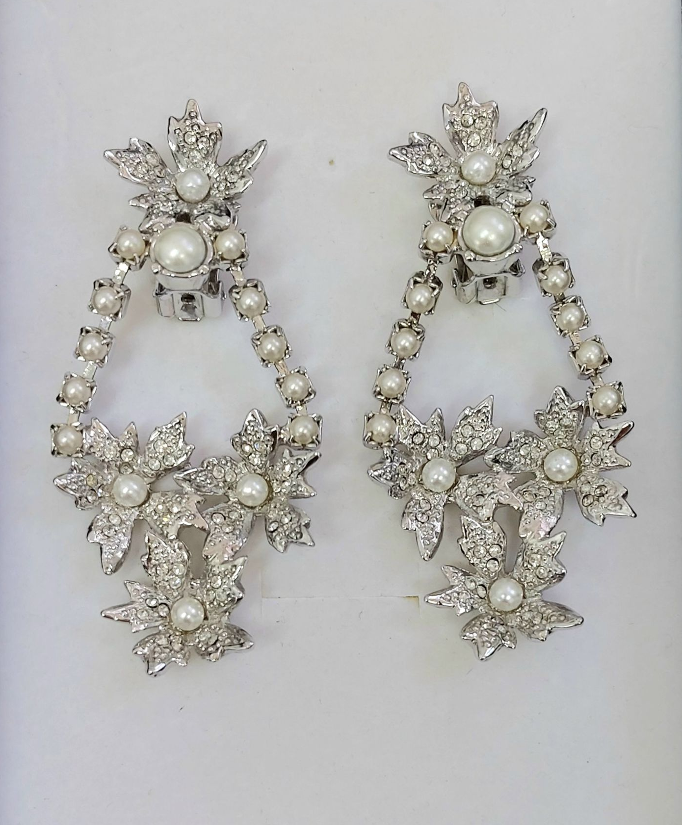 Coppia di orecchini in argento decorati con perle e cristalli con motivo floreale.