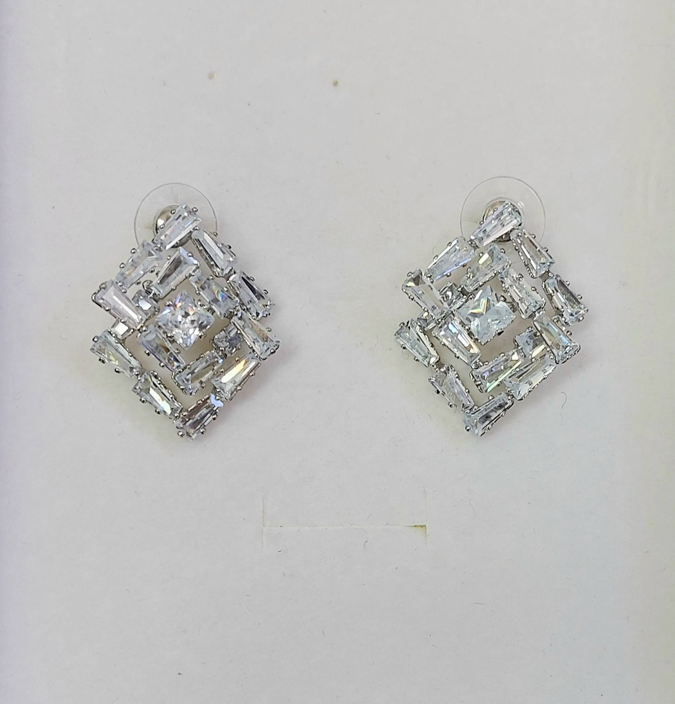 Orecchini a bottone in argento a forma di diamante con numerose piccole pietre trasparenti.