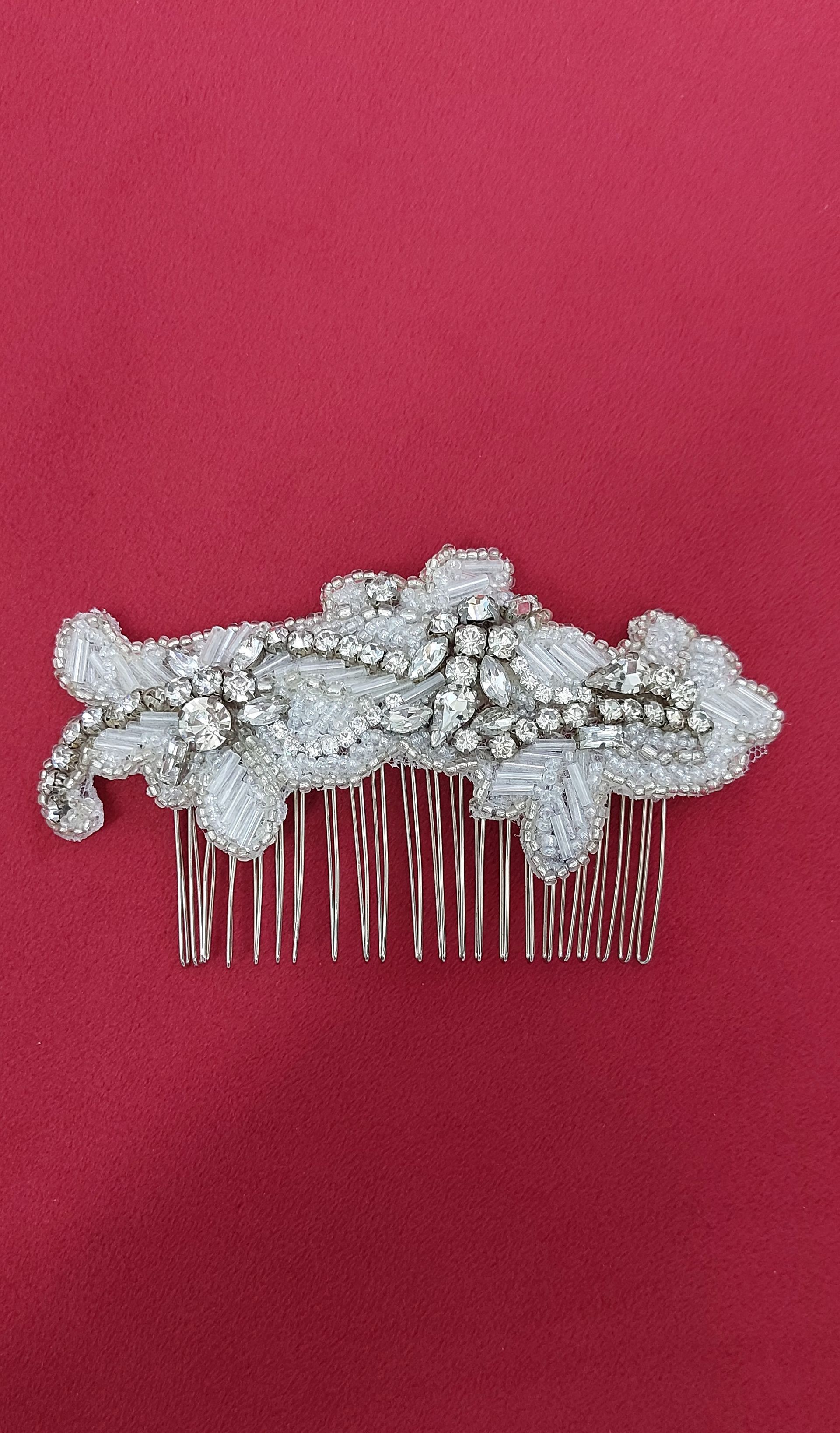Pettine per capelli con perline argentate su sfondo rosso.