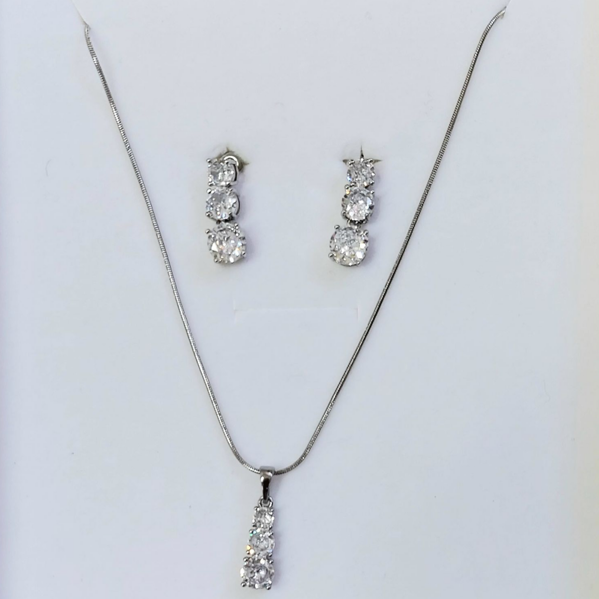 Collana e orecchini in argento con tre pietre trasparenti in ogni pezzo.