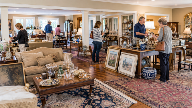 Home décor showroom with patterned rugs, framed art, and shoppers browsing furniture and accessories