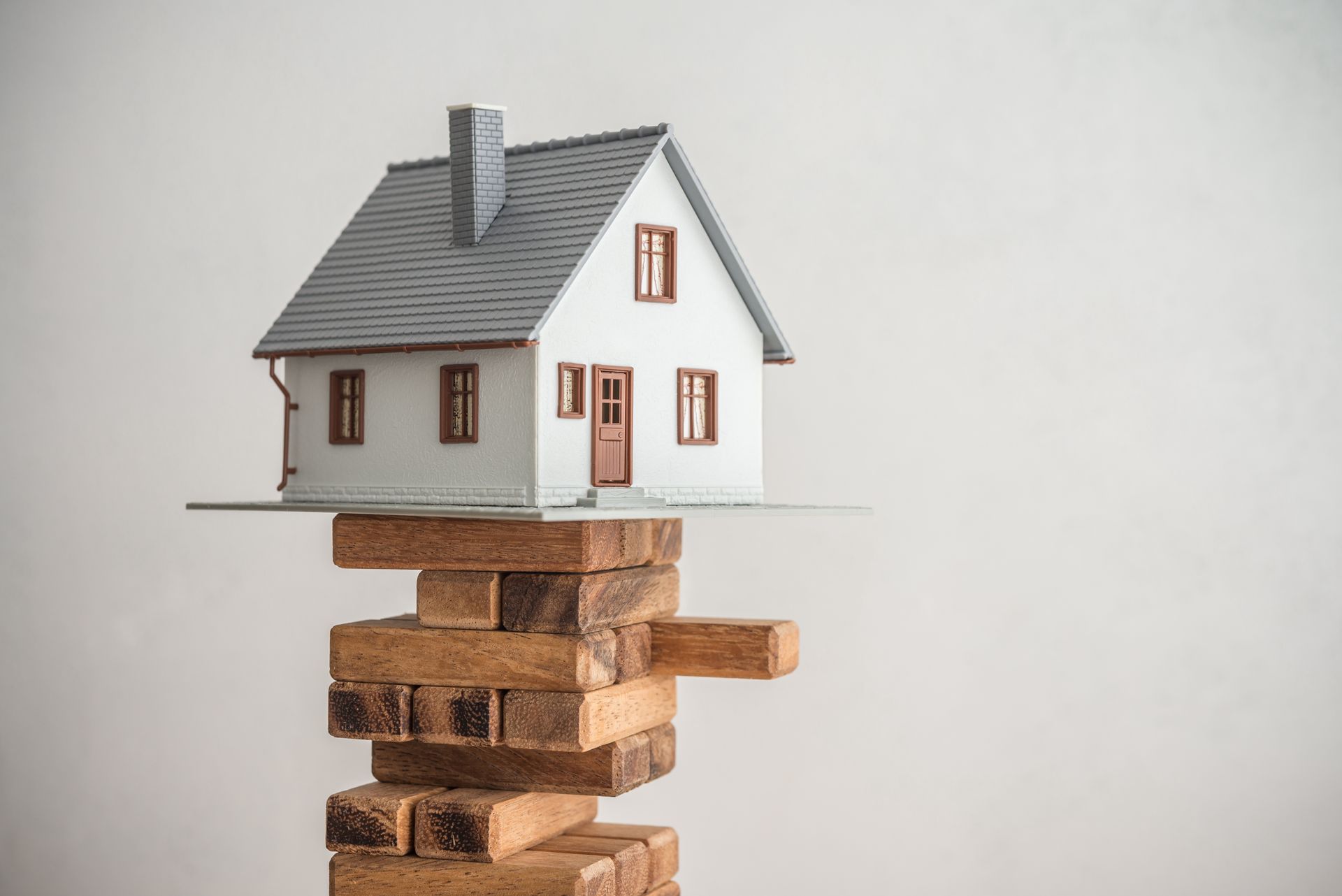 A model house is sitting on top of a stack of wooden blocks.