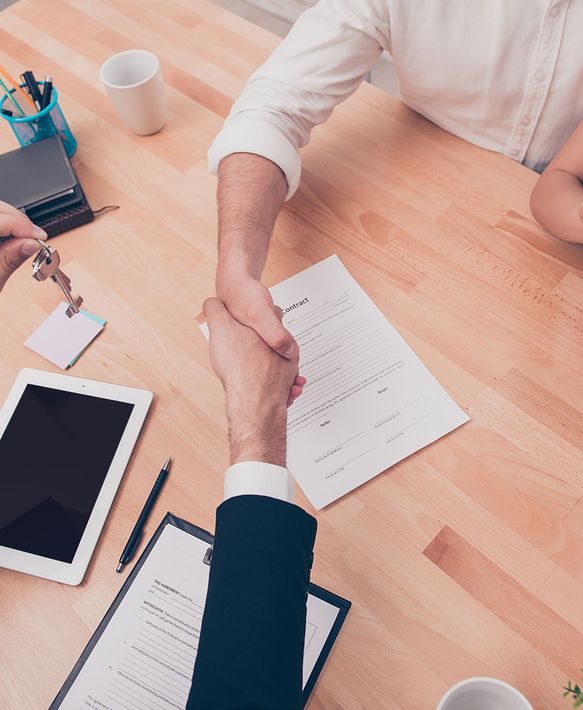 A man is shaking hands with another man at a table.