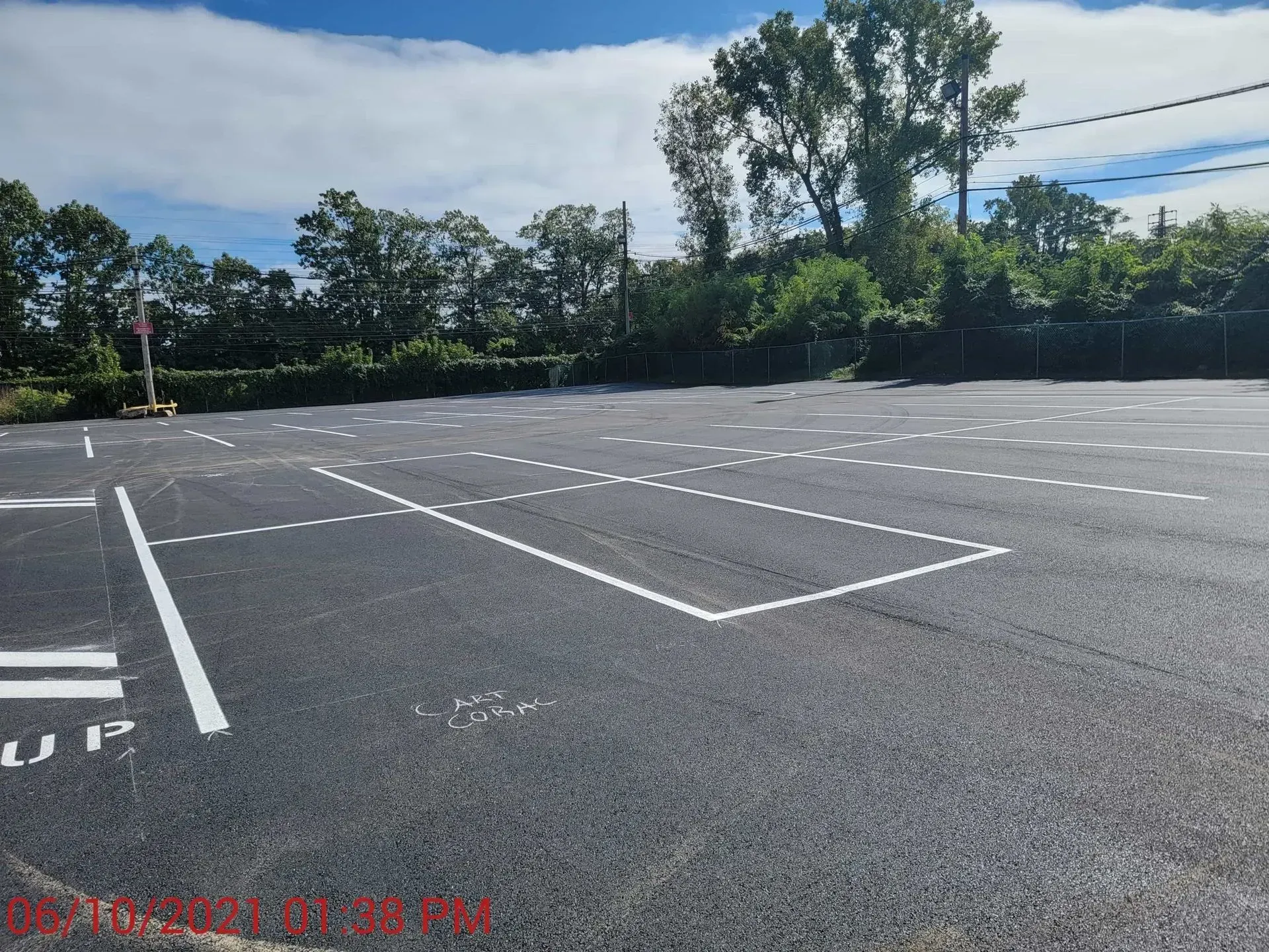 An empty parking lot with trees in the background.