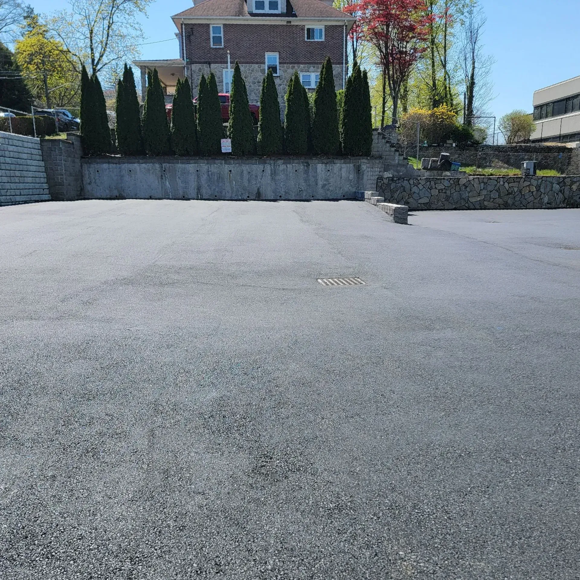 An empty parking lot with a house in the background.