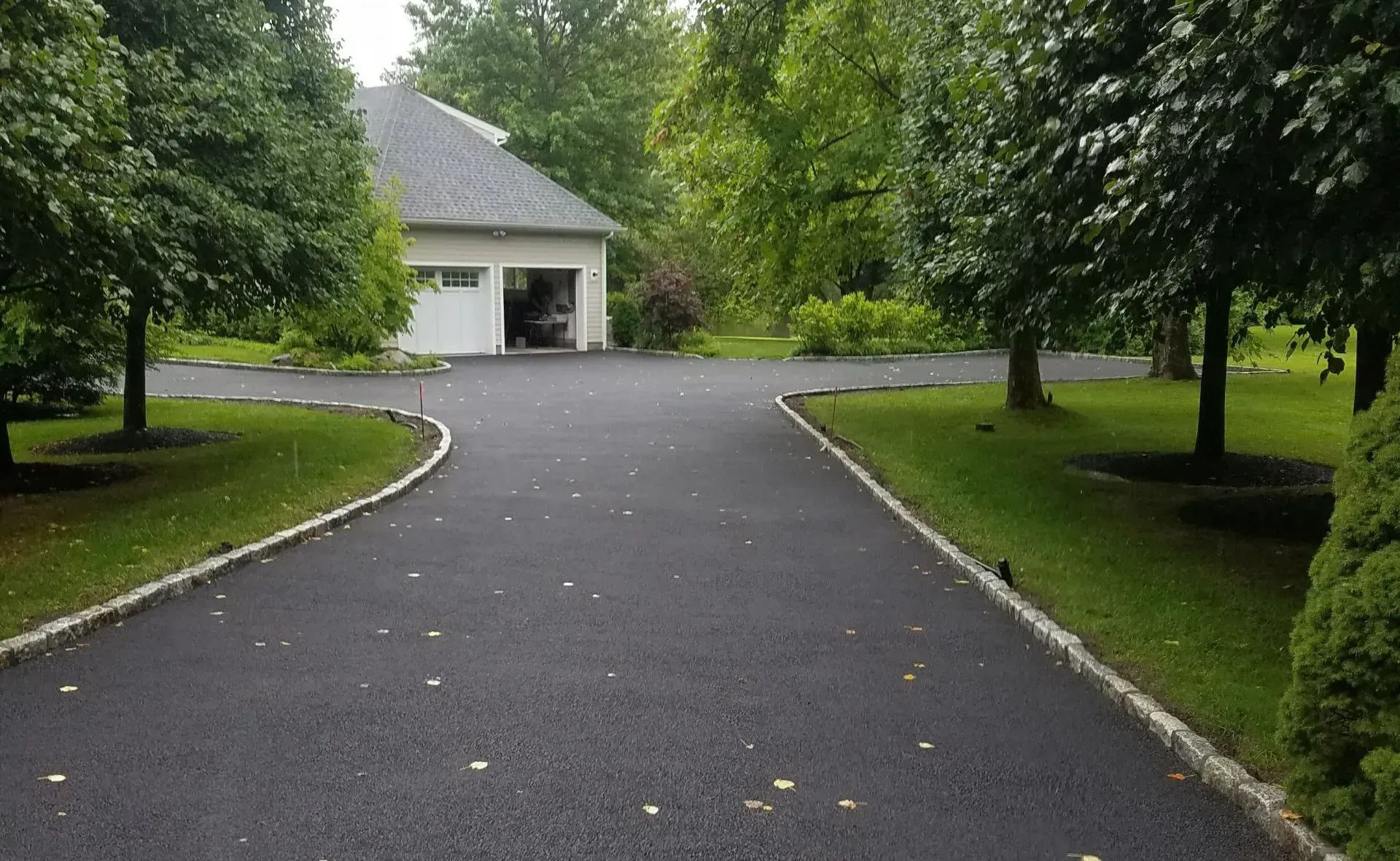 A driveway leading to a garage with trees on both sides.
