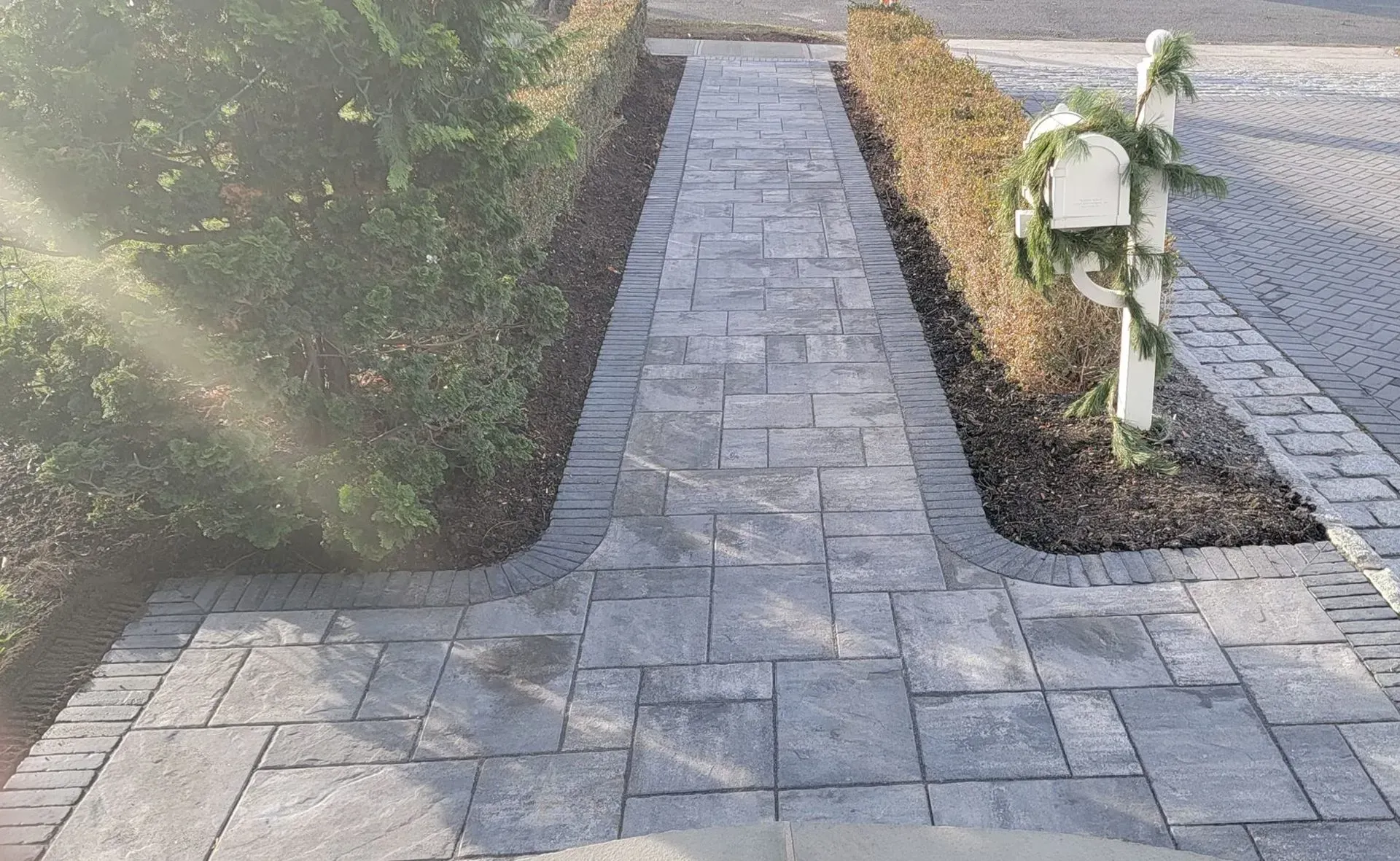 A brick walkway with a mailbox on the side of it.