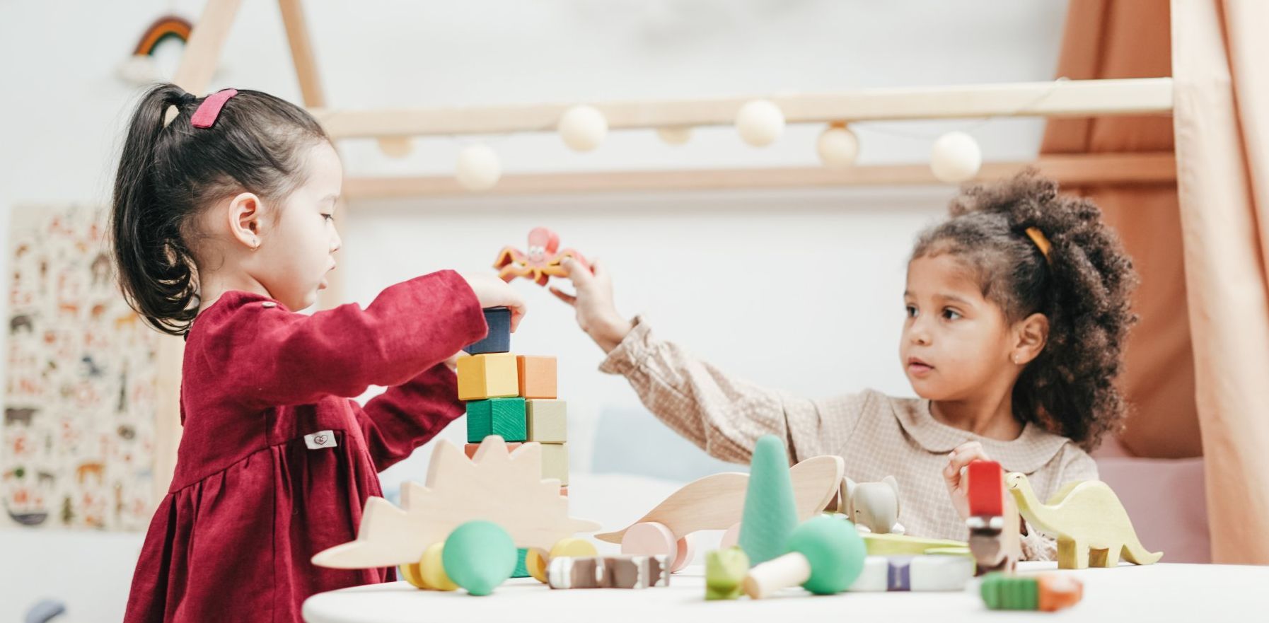 Two little girls are playing with toys at a table.