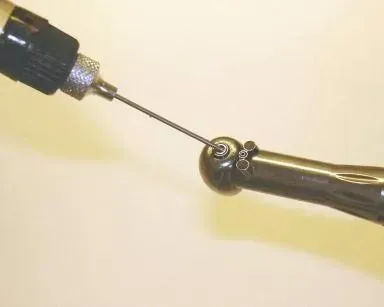 A person is using a drill to drill a hole in a bottle.