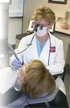 A dentist is examining a patient 's teeth with a magnifying glass.