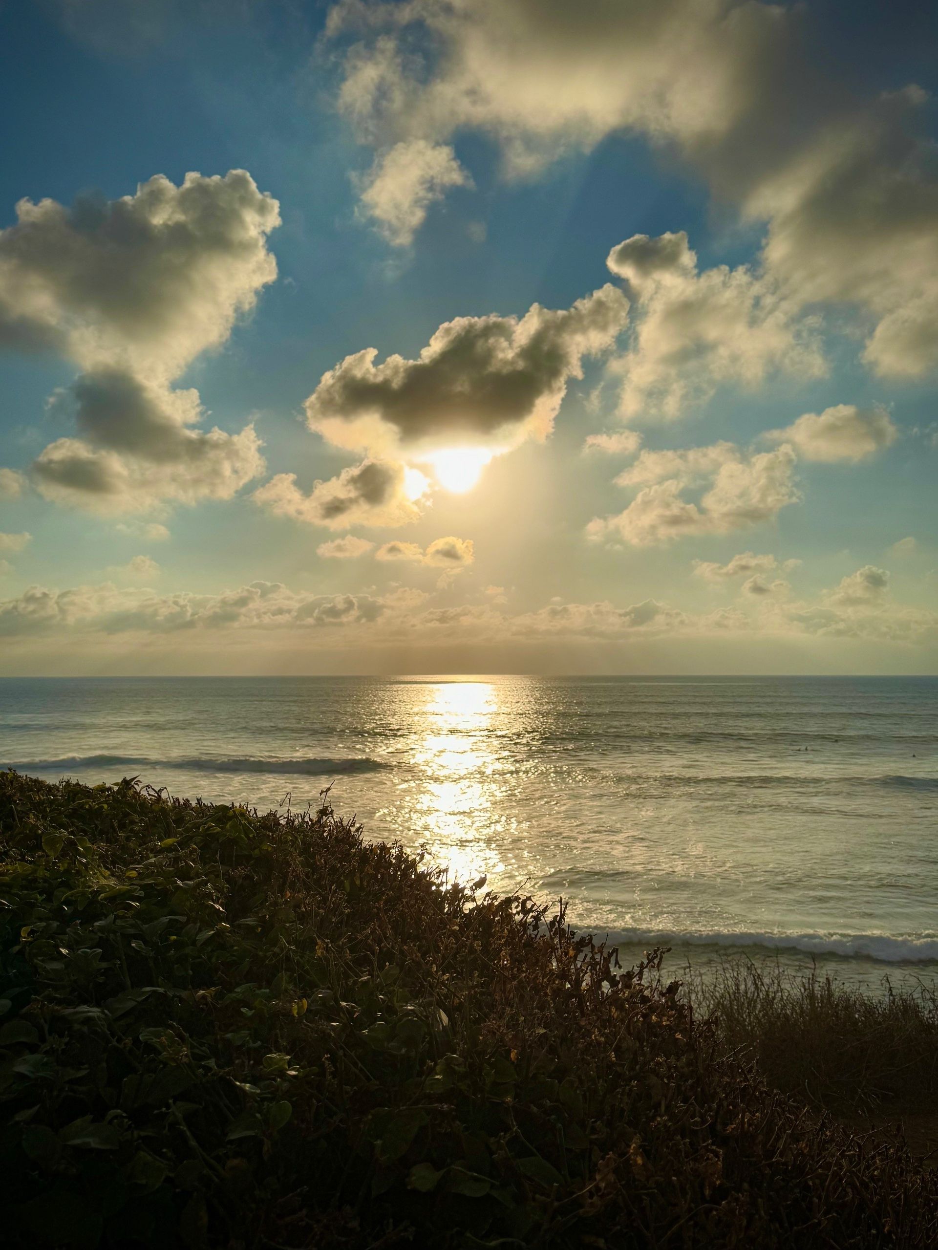The sun is shining through the clouds over the ocean.