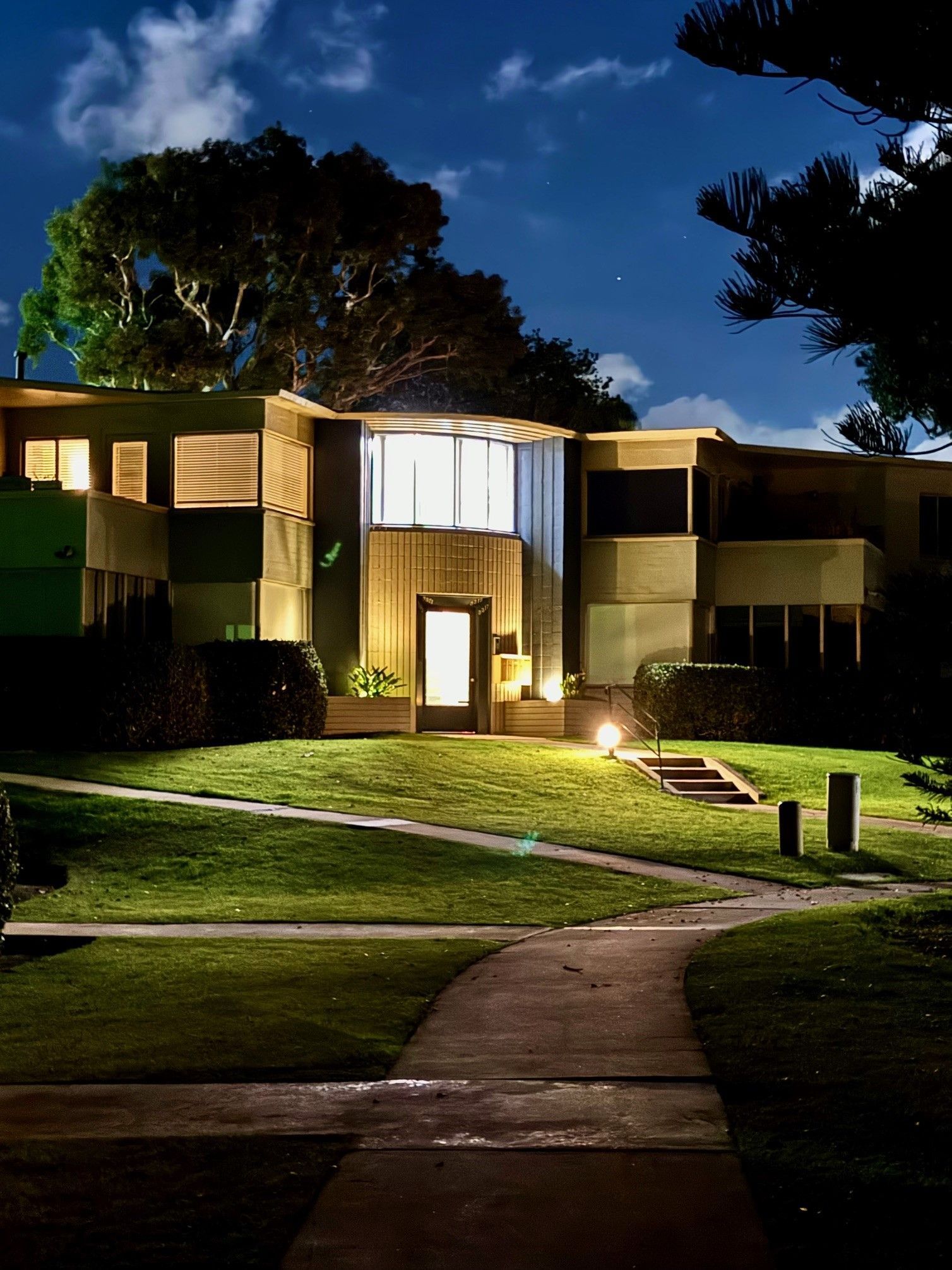 A house is lit up at night with trees in the background